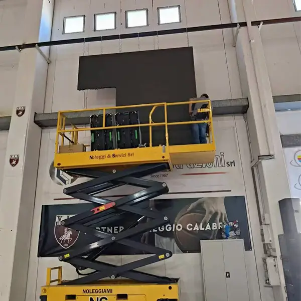 Technicians assembling P3.91 outdoor rental LED display panels using a scissor lift at VIS Reggio Calabria stadium.webp