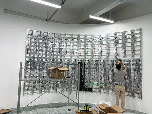 Technician installing curved steel sub-frame for flexible LED display.webp