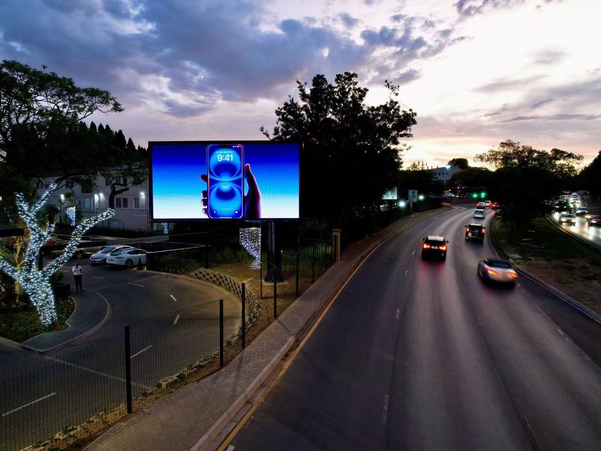 Roadside LED billboard beside a busy road at dusk